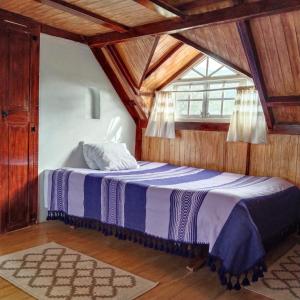 1 dormitorio con 1 cama en una habitación con techos de madera en Cabañita con cocineta y vista a la montaña, en San Pablo Etla