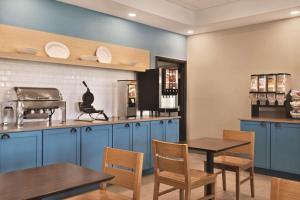 a kitchen with blue cabinets and wooden tables and chairs at Country Inn & Suites by Radisson, Bradenton-Lakewood-Ranch, FL in Bradenton