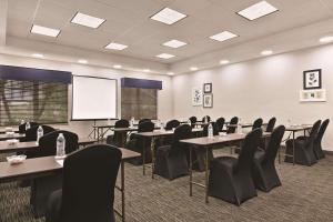 une salle de conférence avec des tables, des chaises et un écran dans l'établissement Country Inn & Suites by Radisson, Tampa-Brandon, FL, à Tampa