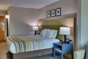 Habitación de hotel con cama grande y mesa con lámpara. en Country Inn & Suites by Radisson, Savannah Gateway, GA en Savannah
