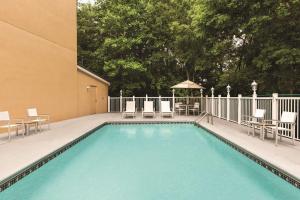 une piscine avec des chaises et des tables ainsi qu'un bâtiment dans l'établissement Country Inn & Suites by Radisson, Lawrenceville, GA, à Lawrenceville