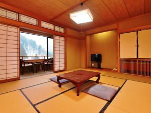 a japanese room with a table and a television at Yunohirakan in Takayama