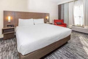 Cama grande en habitación de hotel con silla roja en Country Inn & Suites by Radisson, Smyrna, GA, en Smyrna