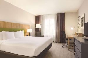 um quarto de hotel com uma grande cama branca e uma secretária em Country Inn & Suites by Radisson, Conyers, GA em Conyers