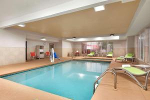 a pool in a hotel room with chairs and tables at Country Inn & Suites by Radisson, Warner Robins, GA in Warner Robins