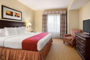アルバニーにあるCountry Inn & Suites by Radisson, Albany, GAのベッドとテレビが備わるホテルルームです。