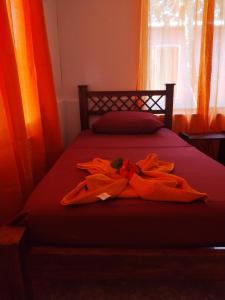 - un lit avec des peignoirs orange et une fenêtre dans l'établissement Anluka-House # 2, à Puerto Jiménez