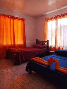 1 dormitorio con 2 camas y cortinas de color naranja en Anluka-House # 2, en Puerto Jiménez