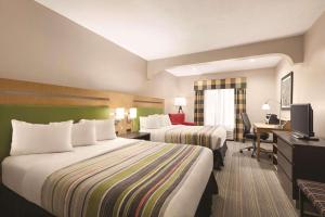 a hotel room with two beds and a desk at Country Inn & Suites by Radisson, Griffin, GA in Griffin