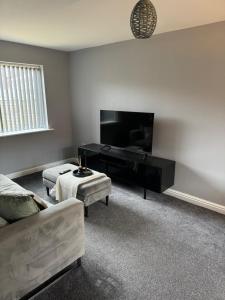 a living room with a couch and a flat screen tv at Lux 3 Bed 10 mins from Centre - Parking & Netflix in Manchester
