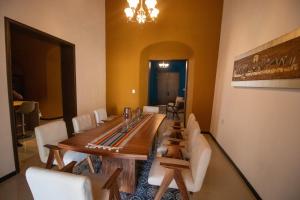 a dining room with a wooden table and white chairs at Viveza - Downtown in Campeche