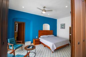 1 dormitorio con paredes azules, 1 cama y 1 silla en Viveza - Downtown en Campeche