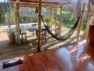 a hammock in a house with a table and chairs at Guacamayo Bed & Breakfast in Máncora