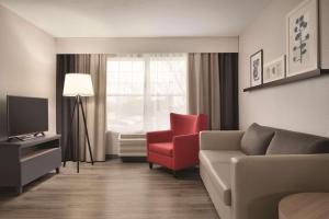 ein Wohnzimmer mit einem Sofa und einem roten Stuhl in der Unterkunft Country Inn & Suites by Radisson, Waterloo, IA in Waterloo