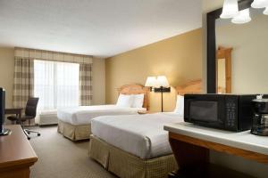 una camera d'albergo con due letti e una televisione di Country Inn & Suites by Radisson, Grinnell, IA a Grinnell
