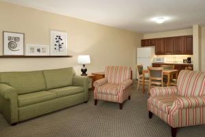 a living room with a couch and two chairs and a kitchen at Country Inn & Suites by Radisson, Grinnell, IA in Grinnell