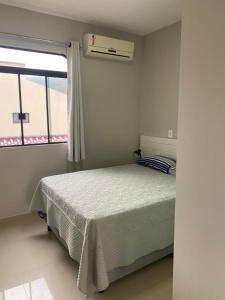 een witte slaapkamer met een bed en een raam bij Residencial Mariano 2 - Vista para praia e Mar in Florianópolis