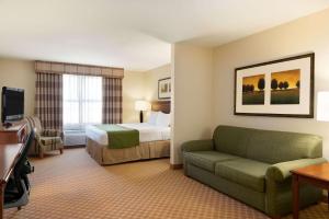 a hotel room with a bed and a couch at Country Inn & Suites by Radisson, Peoria North, IL in Peoria