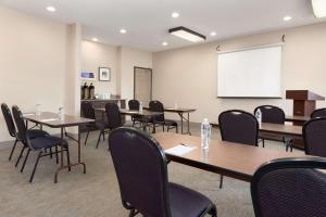 Country Inn & Suites by Radisson, Romeoville, IL في روميوفيله: قاعة اجتماعات مع طاولات وكراسي وطاولة بيضاء