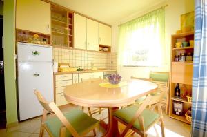 a kitchen with a table and chairs and a refrigerator at Apartments with a parking space Kremenici, Krk - 22191 in Malinska