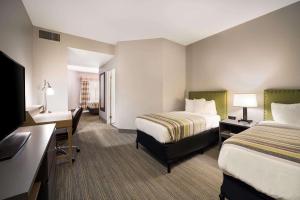 a hotel room with two beds and a desk at Country Inn & Suites by Radisson, Freeport, IL in Freeport