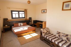 a bedroom with a bed and a chair in it at AdventureKeys Surf Yoga Cowork in Taghazout