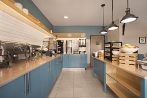 a large kitchen with blue cabinets and a counter at Country Inn & Suites by Radisson, Moline Airport, IL in Moline