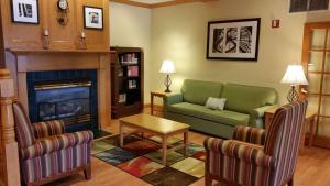 a living room with a green couch and a fireplace at Country Inn & Suites by Radisson, Bloomington-Normal West, IL in Bloomington