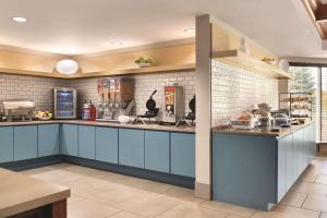 a large kitchen with blue cabinets and white tiles at Country Inn & Suites by Radisson, Portage, IN in Portage