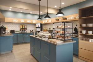 a kitchen with blue cabinets and a counter with pastries at Country Inn & Suites by Radisson, Indianapolis South, IN in Indianapolis