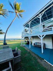 a building with a picnic table and a palm tree at Absolute Beachfront Bowen Beach House-family time in Bowen