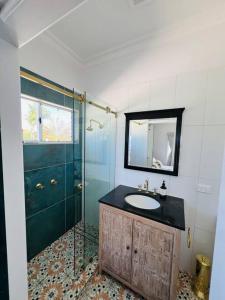 uma casa de banho com um lavatório e uma cabina de duche em vidro. em Absolute Beachfront Bowen Beach House-family time em Bowen