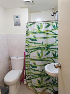 a bathroom with a toilet and a shower curtain with leaves at Seawind Condominiums Tower 1,3,4,5 in Davao City