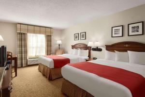 a hotel room with two beds and a flat screen tv at Country Inn & Suites by Radisson, Louisville South, KY in Shepherdsville