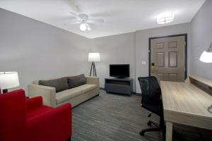 ein Wohnzimmer mit einem Sofa, einem Tisch und einem TV in der Unterkunft Country Inn & Suites by Radisson, Cincinnati Airport, KY in Hebron