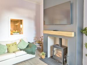 a living room with a white couch and a fireplace at Elfin Cottage - Uk7810 in Coirantee
