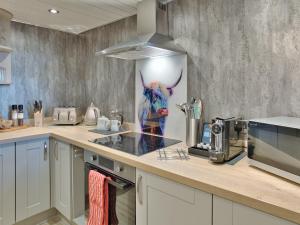 a kitchen with a statue of a cow on the wall at Elfin Cottage - Uk7810 in Coirantee