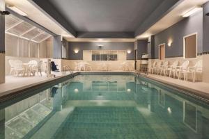 uma grande piscina com cadeiras e mesas em Country Inn & Suites by Radisson, Grand Rapids East, MI em Grand Rapids