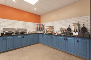 Country Inn & Suites by Radisson, Grand Rapids East, MI في غراند رابيدز: مطبخ كبير مع خزائن زرقاء وجدران برتقالية