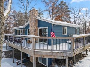 een blauw huis met een terras met een Amerikaanse vlag bij Eagles Rest On Whitefish in Pine River