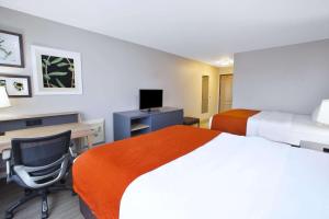 Habitación de hotel con 2 camas y escritorio en Country Inn & Suites by Radisson, Big Rapids, MI, en Big Rapids