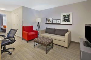 un soggiorno con divano e sedia rossa di Country Inn & Suites by Radisson, Big Rapids, MI a Big Rapids