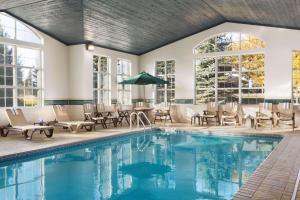 una piscina con sillas, mesas y ventanas en Country Inn & Suites by Radisson, Eagan, MN, en Eagan