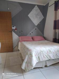 um quarto com uma cama grande e almofadas cor-de-rosa em Sobrado aconchegante. em Cascavel