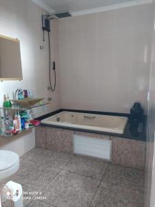 a bathroom with a bath tub and a toilet at Sobrado aconchegante. in Cascavel