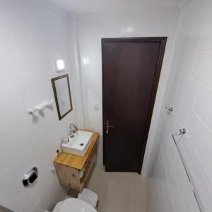a bathroom with a toilet and a sink and a door at Apartamento Aconchegante Centro Serra Negra in Serra Negra