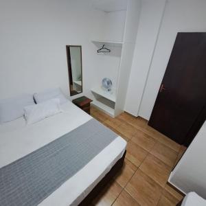 um quarto branco com uma cama e um espelho em Apartamento Aconchegante Centro Serra Negra em Serra Negra
