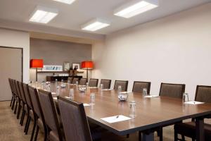 Country Inn & Suites by Radisson, Roseville, MN في روزفيل: قاعة اجتماعات كبيرة مع طاولة وكراسي طويلة