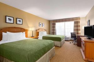 a hotel room with two beds and a flat screen tv at Country Inn & Suites by Radisson, Rochester South, MN in Rochester