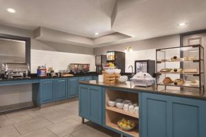 a large kitchen with blue cabinets and a counter with food at Country Inn & Suites by Radisson, Cottage Grove, MN in Cottage Grove